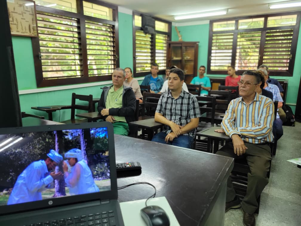 Personas sentadas en pupitres, participando en el acto por el 69 aniversario del Jardín Botánico.