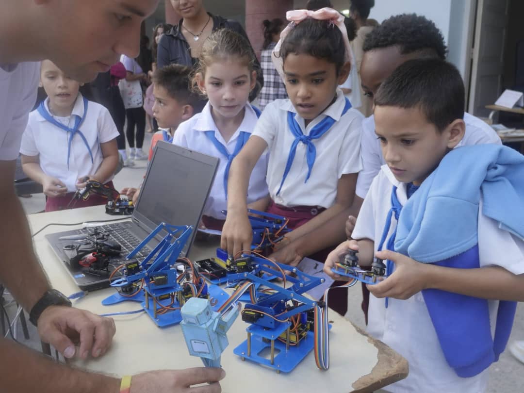 Imagen de estudiantes del proyecto de Robótica Educativa mostrando sus creaciones a niños y niñas